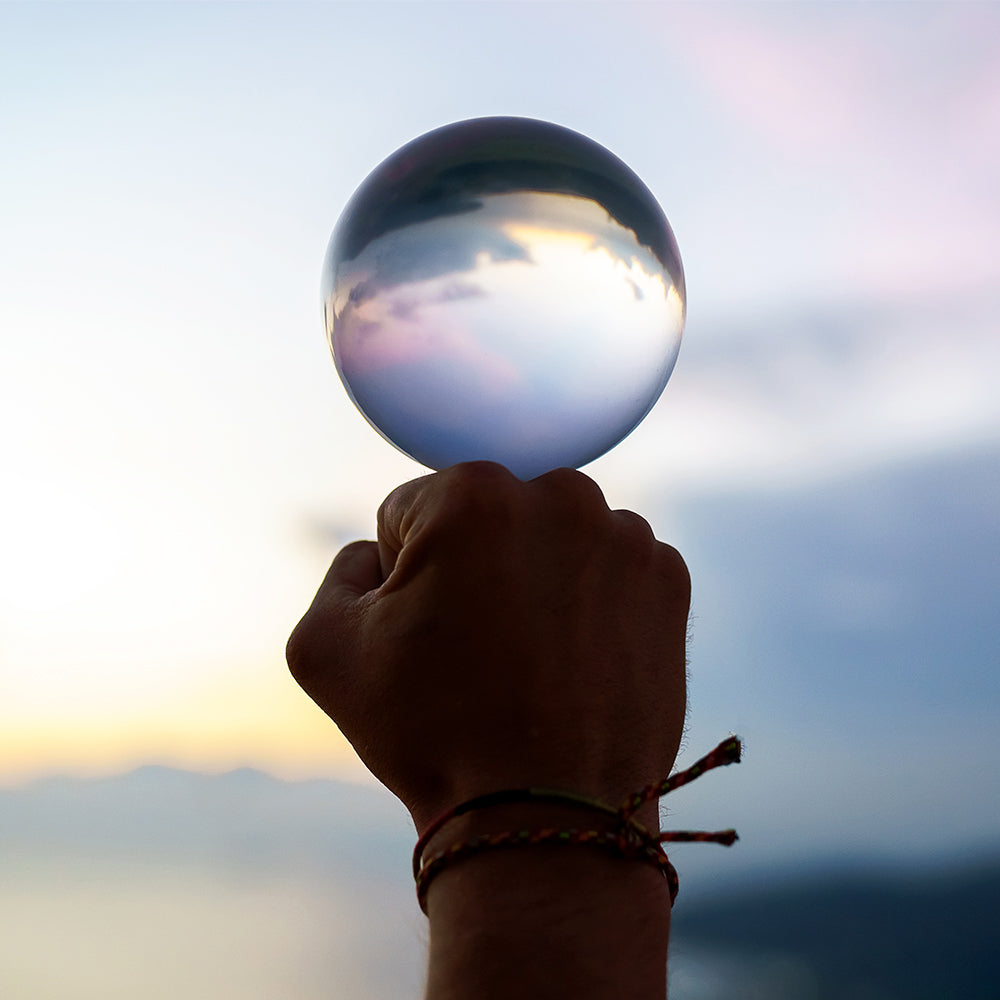 Ball holding on fist; Inverted panorama of sky in reflection of ball