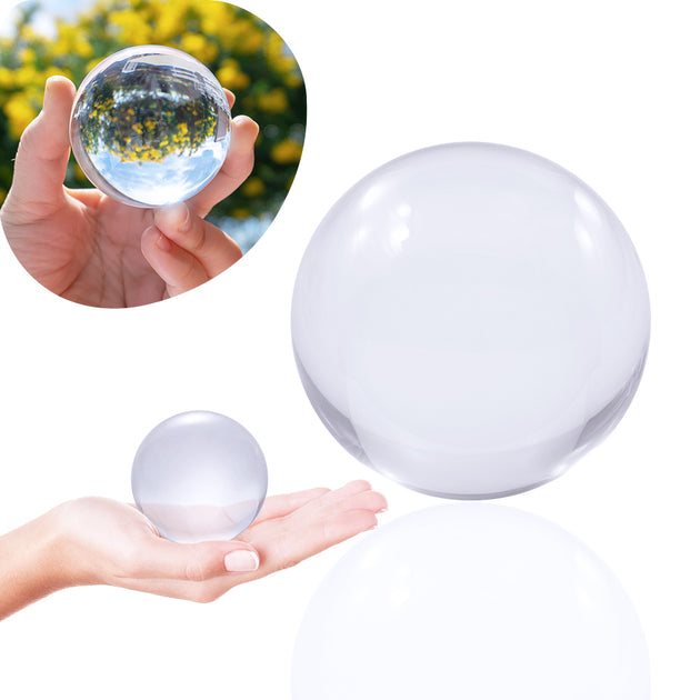 60mm Clear Contact Juggling Ball; Contact Ball lying in Hand; Inverted panorama of yellow flowers in reflection of ball. 