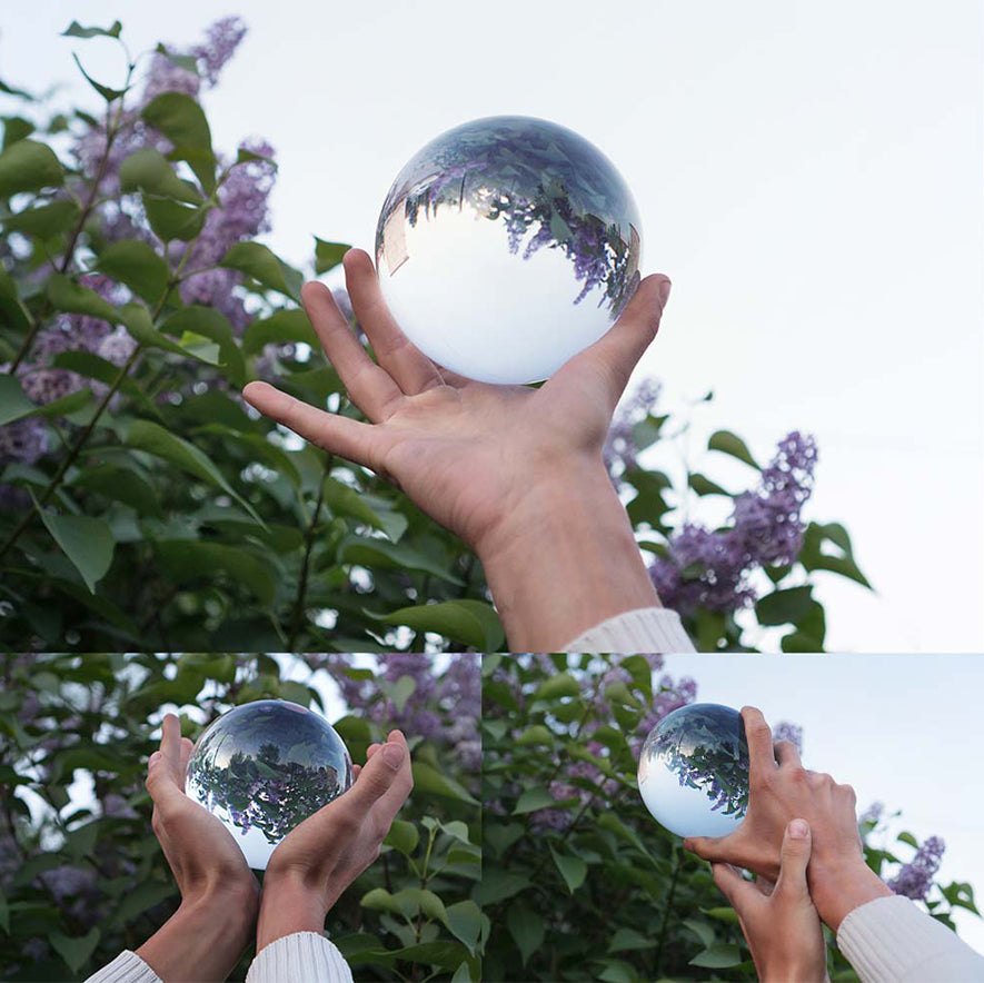 90mm Juggle Dream Crystal Clear Contact Juggling Ball in hand with sky and olive bush background