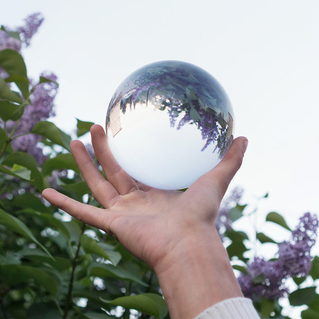 Acrylic Contact juggling ball in hand;  Inverted panorama of olive bush in reflection of ball