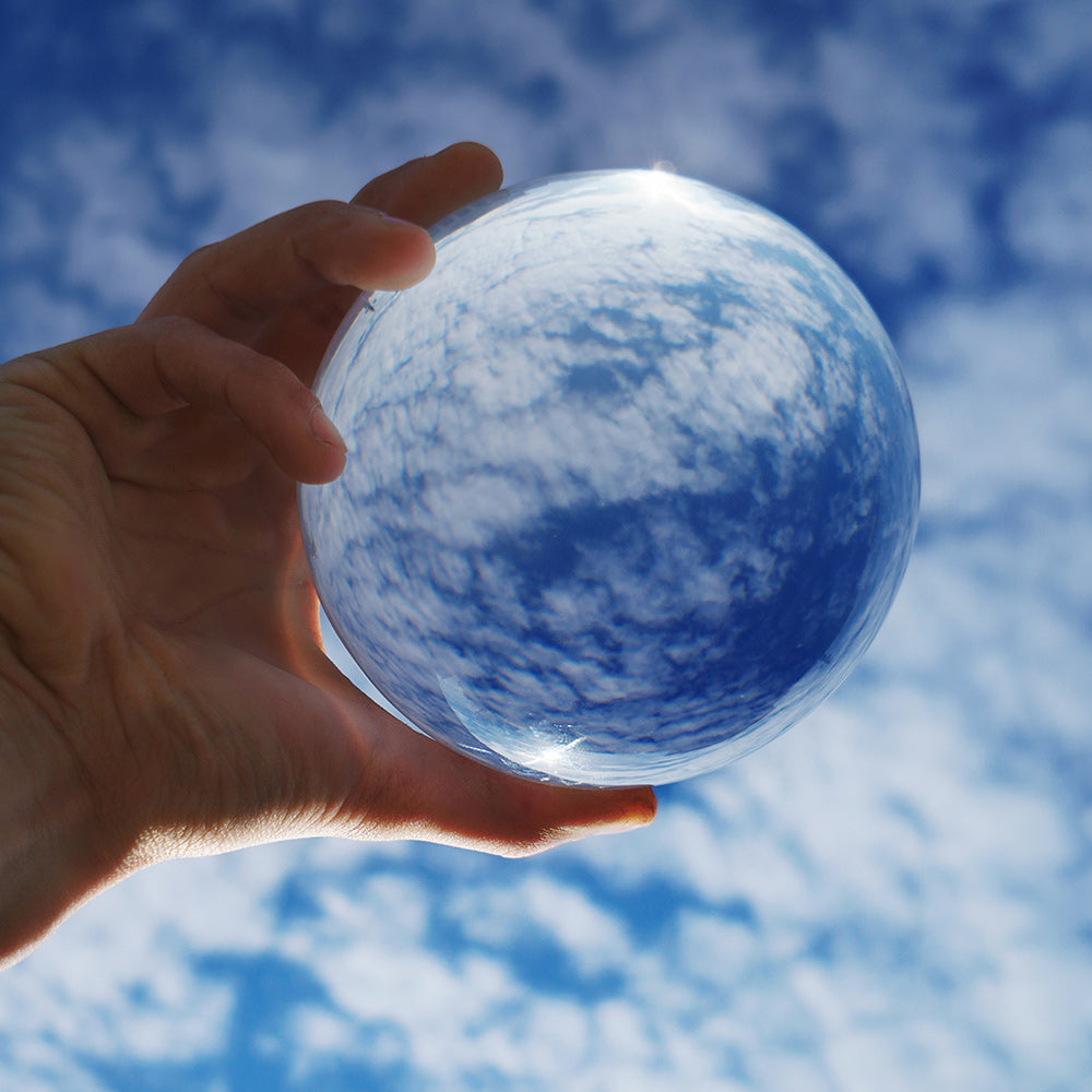 Close-up of hand holding 90mm Clear Contact Juggling Ball in sky background; Inverted panorama of sky in reflection of ball