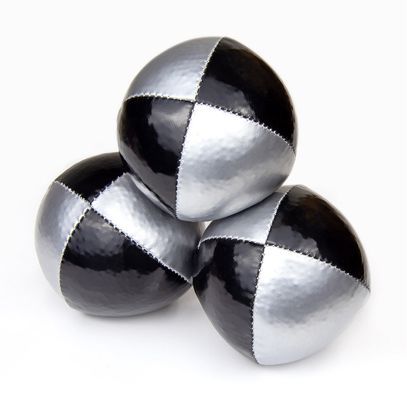 One ball on top of other two juggling balls - silver / black colours