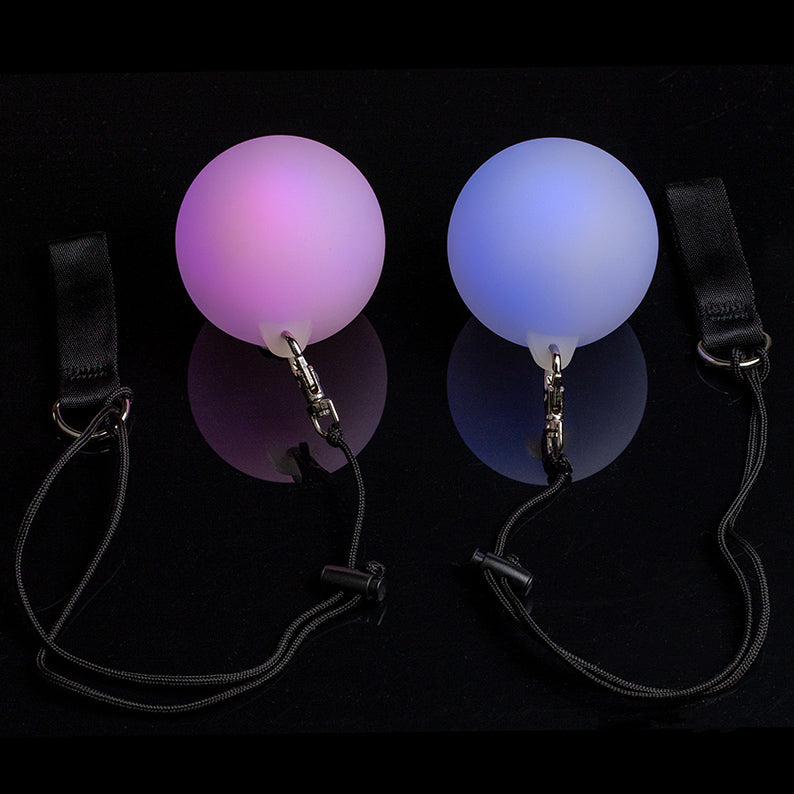 A pair of LED Poi glowing in pink and blue in black background
