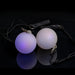 A pair of Oddballs Soft Strobe LED Glow Poi On Black String in black background